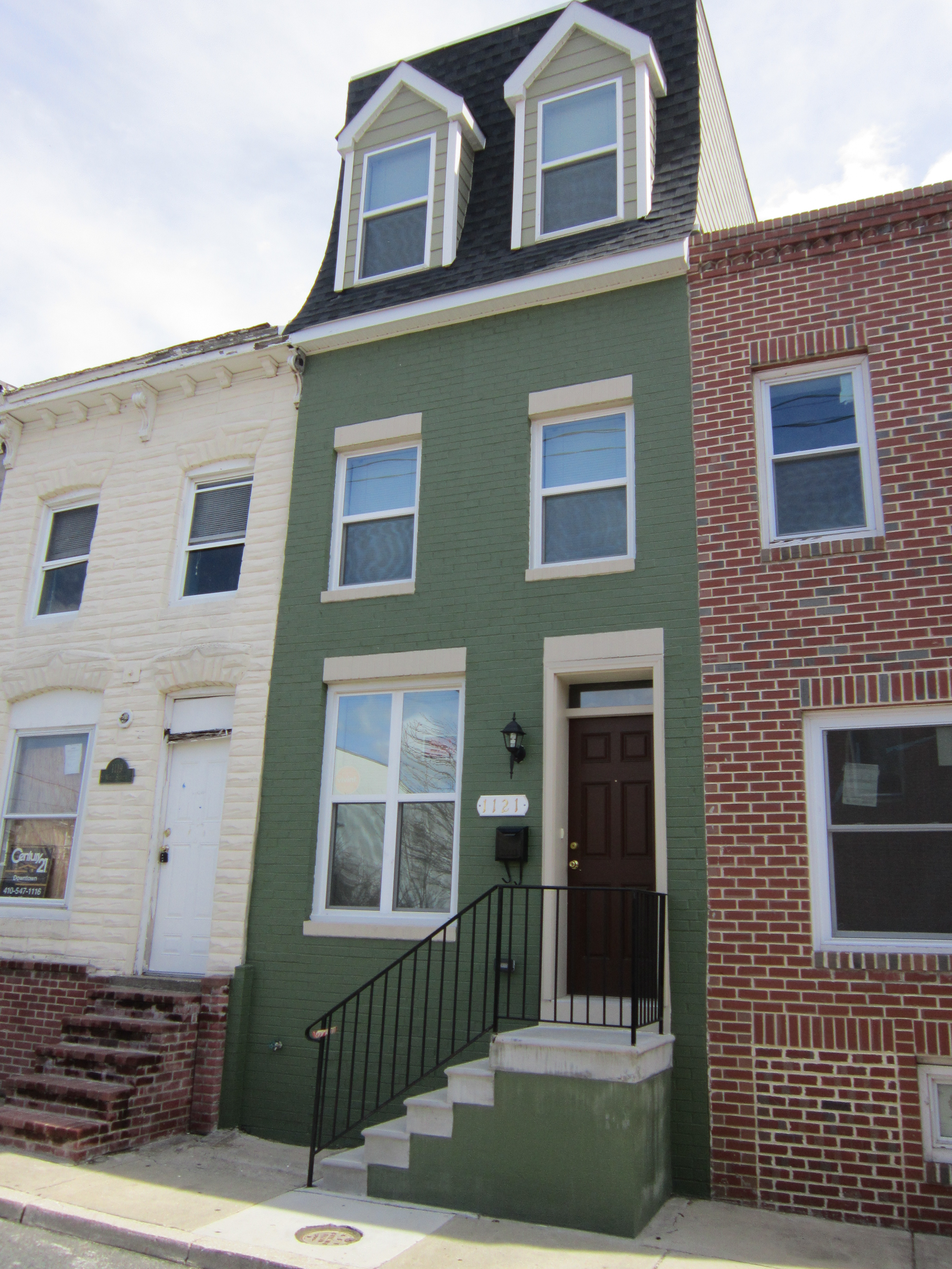 1121 Ward Street after renovation. Baltimore City rowhome with an added floor, new stairs, and painted green and black.