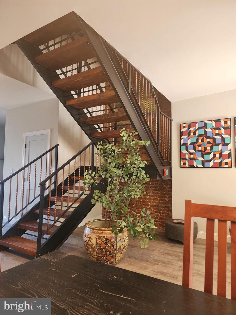 3504 Woodbrook Avenue interior after renovation. Steel staircase, exposed brick walls, colorful artwork. 
