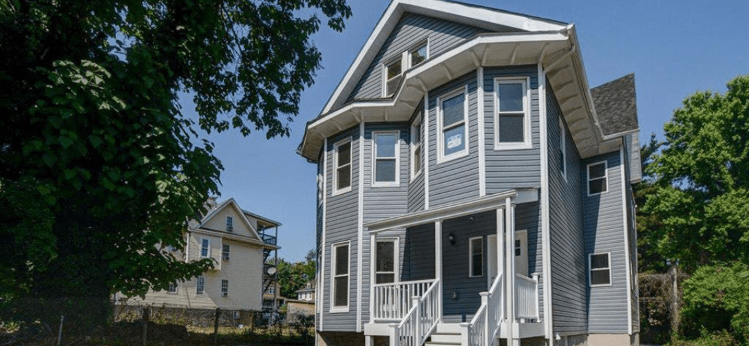 2125 Denison Street after renovation. Two-unit home with gray siding.